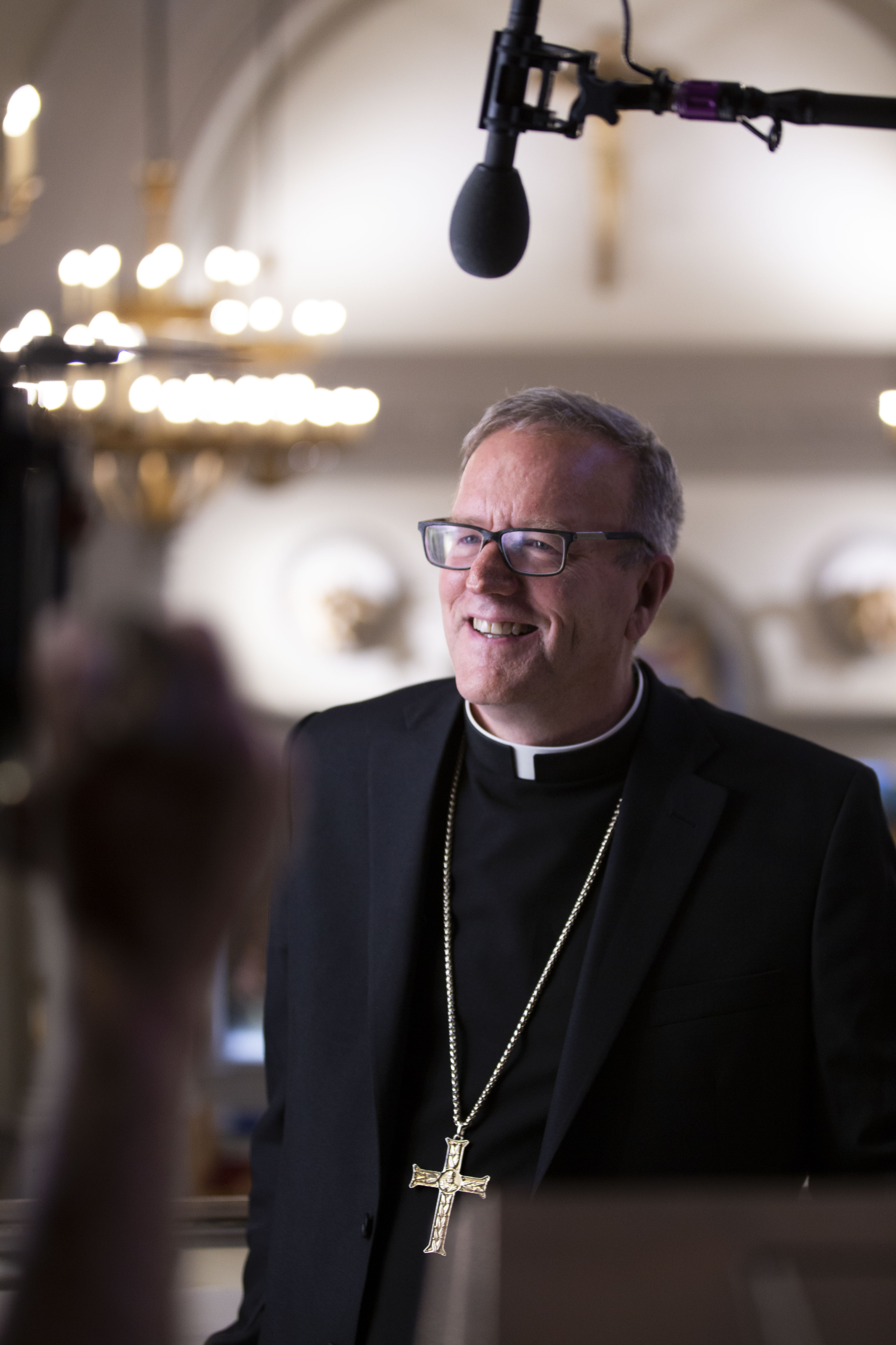Bishop Barron with a microphone and smiling