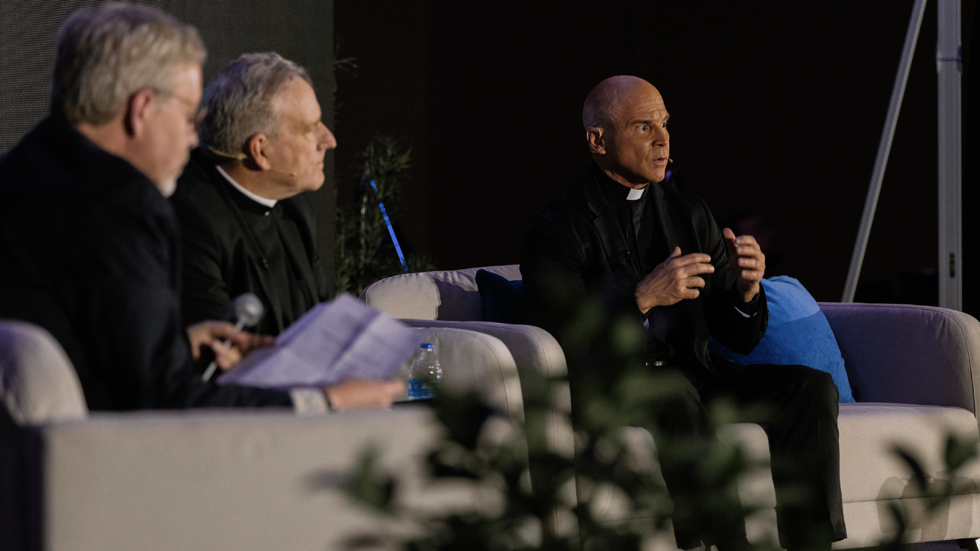 Three men lean forward